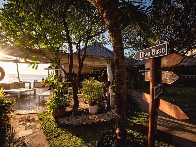 Gezellig hotelgebied met een wegwijzer naar de duikbasis in het licht van de ondergaande zon.