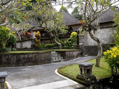 Ścieżka w ogrodzie z drzewami i kamiennymi latarniami przed tradycyjnymi budynkami.