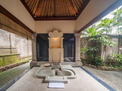 Zadbany teren zewnętrzny z dekoracyjną kamienną fontanną i tropikalnymi roślinami w hotelowym otoczeniu.