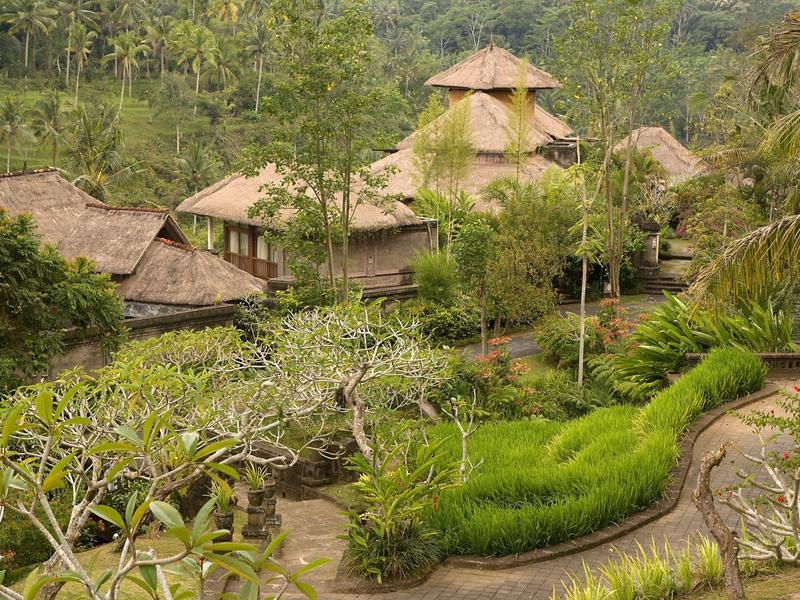 Hotel z tradycyjnymi dachami z trzciny otoczony bujnym ogrodem i tropikalną roślinnością.