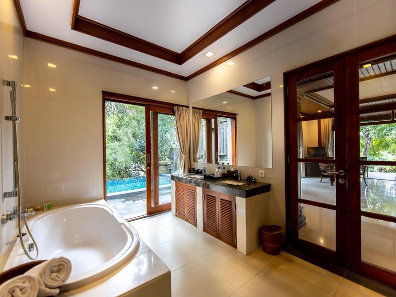 Nowoczesna łazienka z wanną, podwójną umywalką i dużym oknem z widokiem na zieleń.