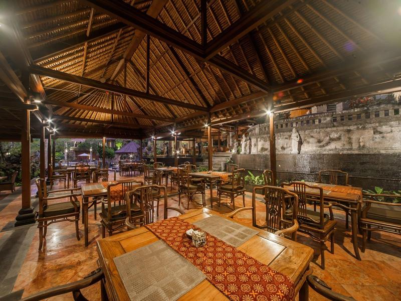 Przytulny otwarty taras restauracyjny z drewnianym dachem i ciepłym oświetleniem nocą.