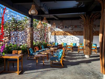 Area interna accogliente con sedie e tavoli, decorata con luci a stringa e piante.