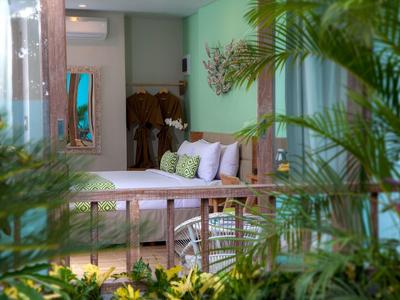 Accogliente balcone dell'hotel con panca di legno, cuscini e vista su piante verdi.