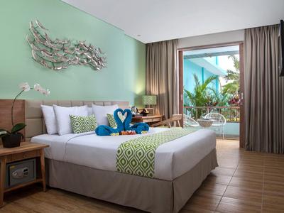 Camera d'hotel luminosa con letto matrimoniale, balcone e vista tropicale.