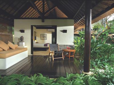 Otwarta weranda z miejscem do siedzenia z widokiem na bujną zieloną roślinność, część tropikalnego ośrodka.