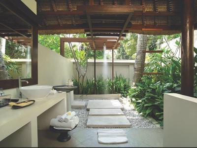 Otwarta łazienka z drewnianą konstrukcją, ozdobnymi umywalkami i widokiem na bujny ogród.