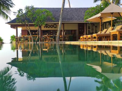 Spokojny basen z leżakami i barem w tropikalnym hotelu.