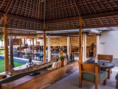 Pabellón abierto con muebles de madera y techo tradicional, rodeado de jardín y área al aire libre.