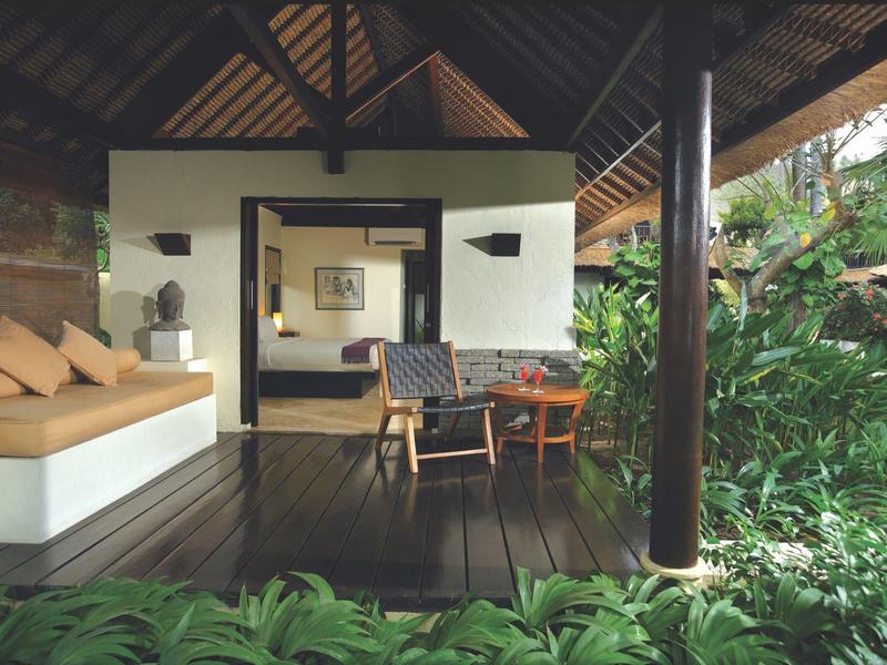 Otwarta weranda z miejscem do siedzenia z widokiem na bujną zieloną roślinność, część tropikalnego ośrodka.