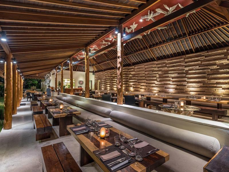 Rustykalna restauracja z drewnianymi stołami, przytulnym oświetleniem i dekoracyjnymi drewnianymi belkami na suficie.