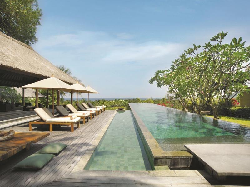 Nowoczesny basen na świeżym powietrzu z leżakami i parasolami w spokojnym otoczeniu hotelu.