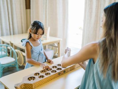 Child playing a traditional game at a bright table in a hotel setting