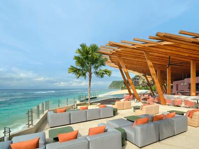Modern beachside restaurant with lounge seating and ocean view with a palm tree.