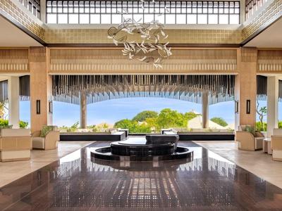 Bright hotel lobby with central fountain and view of green outdoor area
