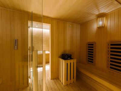 Bright wooden sauna with glass door, benches, and electric heater.