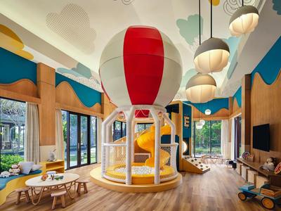 Indoor bright colorful children's play area with hot air balloon structure and wooden furniture.