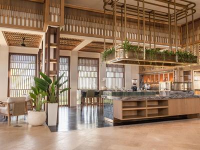 Brightly furnished restaurant area with wooden accents and plants in a hotel setting.
