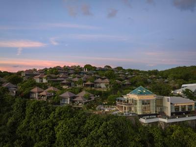 Widok na ośrodek z wieloma budynkami na zalesionym wzgórzu o zachodzie słońca.