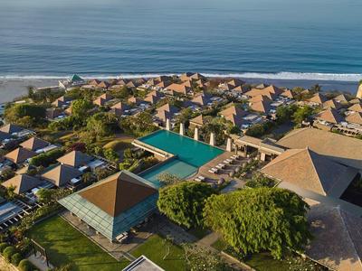 Luxury resort with pool and bungalows by the sea on a sunny day.