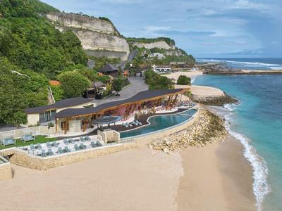 Luxury beach resort with pool, surrounded by cliffs and blue sea.
