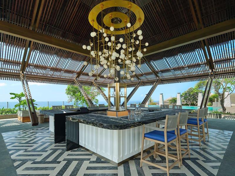 Open lounge area with bar, stools, and sea view under a covered roof.