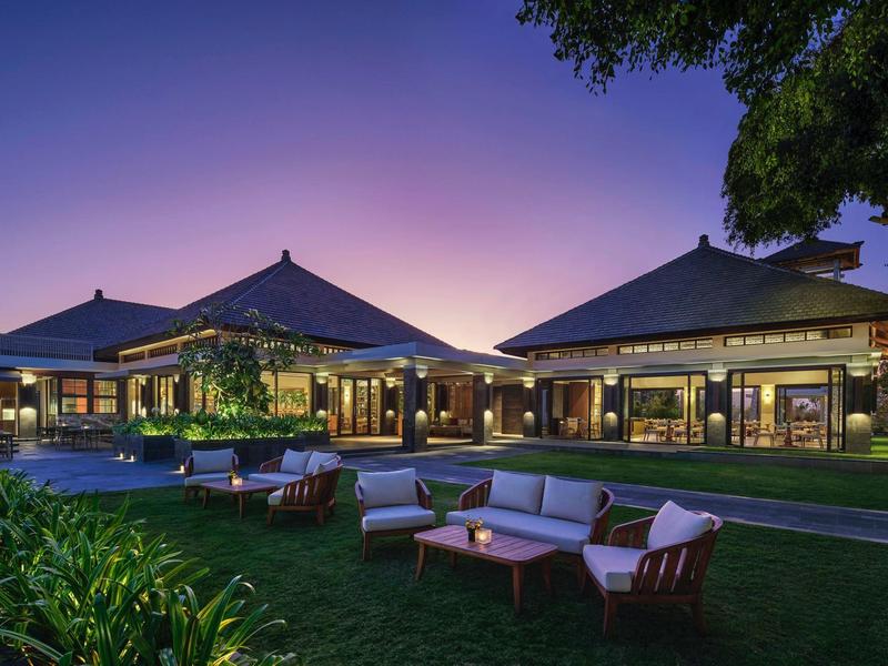 Luxury hotel with traditional roofs and comfortable outdoor seating at sunset.