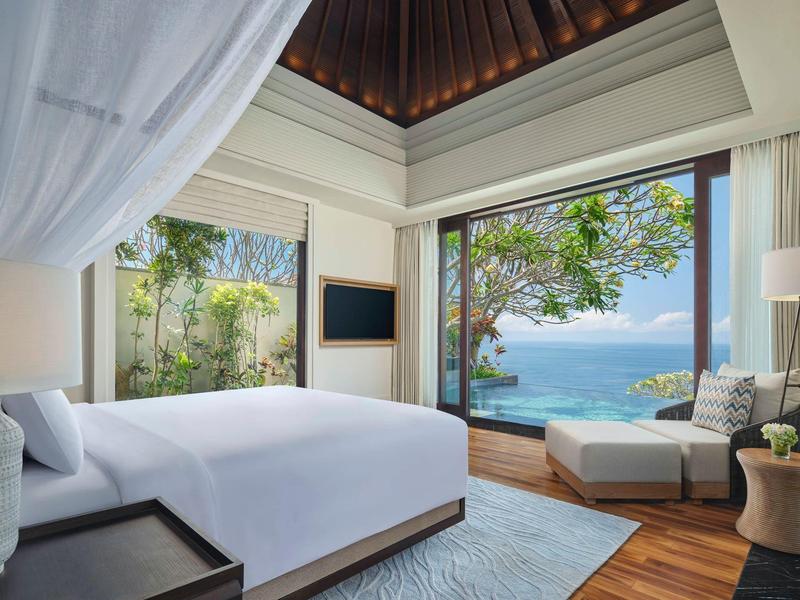 Modern bedroom with sea view and access to terrace with lounge chair.