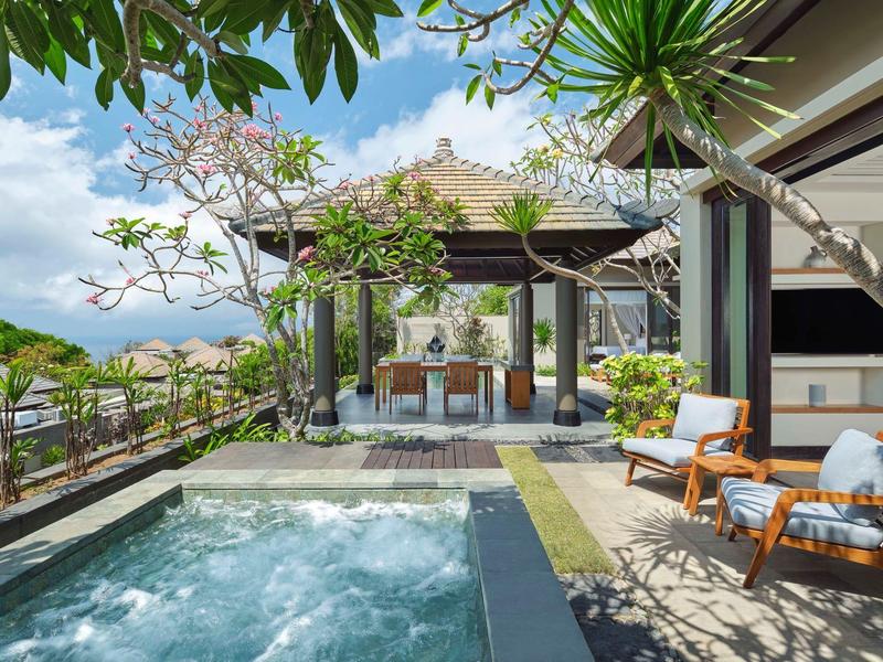 Luxurious outdoor pool and spa area with lounge chairs in tropical hotel garden.