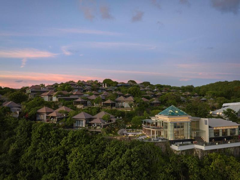 Luxury resort with multiple villas on forested hill at sunset