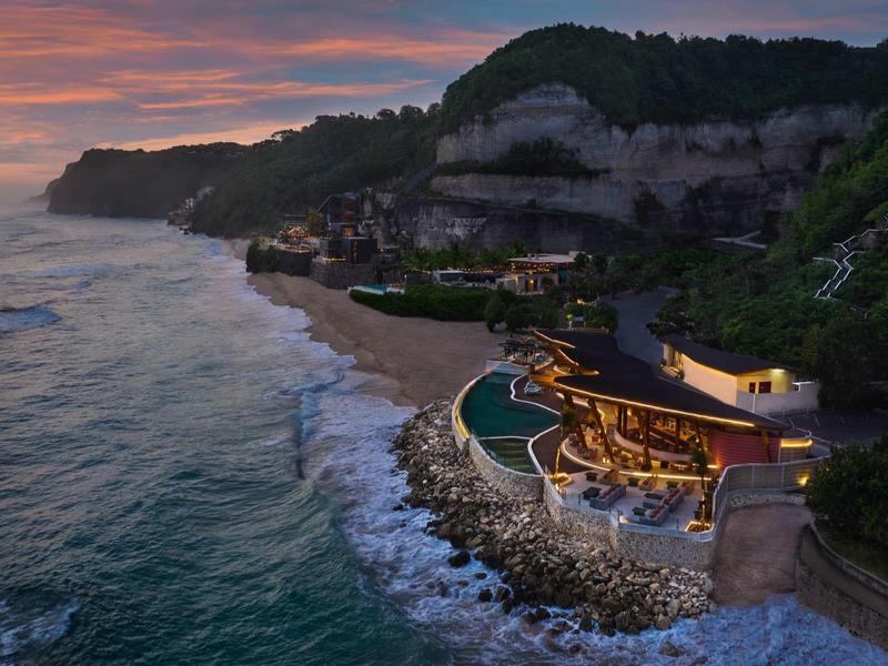 Luxury resort with pool on rocky coast at sunset