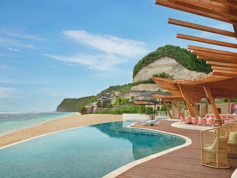 Modern pool area with lounge chairs and mountain view at a beach resort.