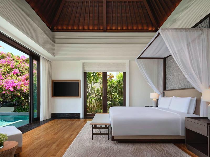 Modern bedroom with canopy bed and open access to garden and swimming pool.