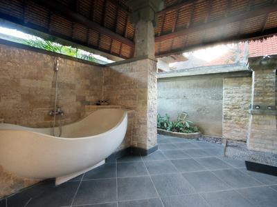 Salle de bain extérieure moderne avec baignoire indépendante et murs en pierre sous toit en bois.