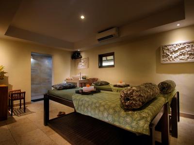 Salle de soin confortable avec tables de massage et éclairage chaleureux dans un spa.