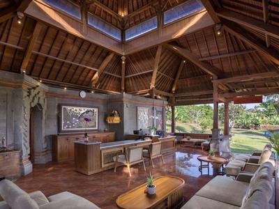Grand salon avec plafond à poutres en bois, mobilier moderne et vue sur le jardin.