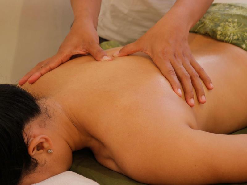 Personne allongée sur le ventre recevant un massage du dos dans un cadre relaxant.