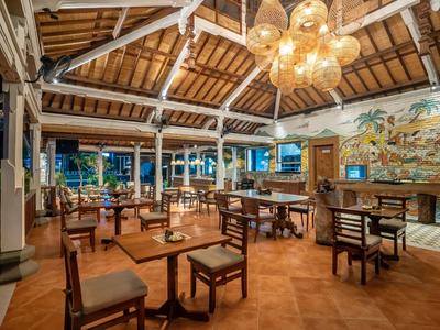 Restaurace s dřevěnými stoly a židlemi pod vysokým dřevěným klenutým stropem s lustry.