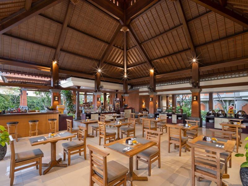 Przestronna restauracja z drewnianymi meblami i otwartym dachem w tropikalnym stylu.