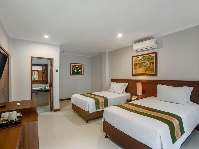 Pokój hotelowy z dwoma łóżkami pojedynczymi, TV, klimatyzacją i nowoczesnym wystrojem.