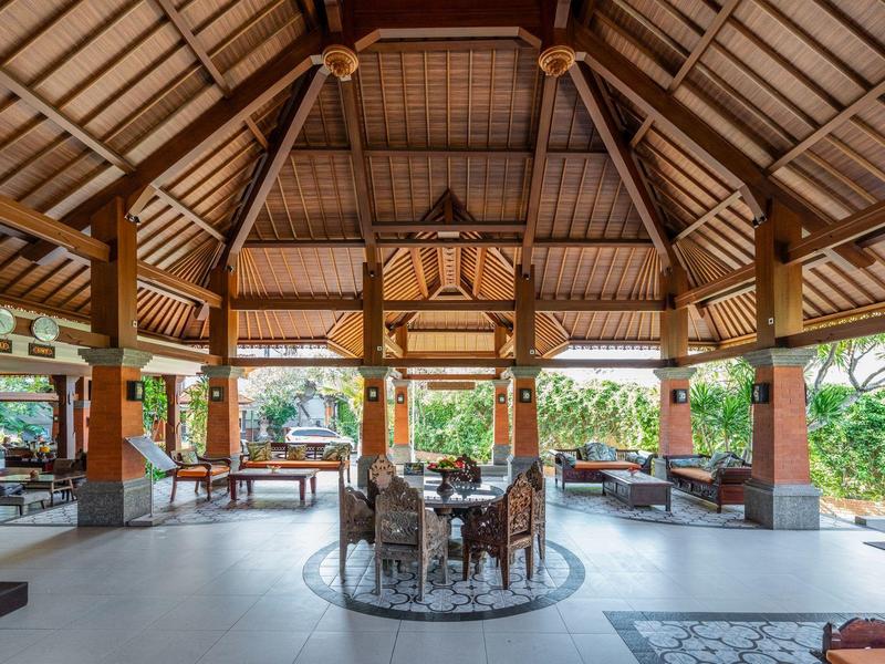 Otwarty pawilon z stołem i krzesłami do jadalni otoczony naturą i drewnianymi konstrukcjami.