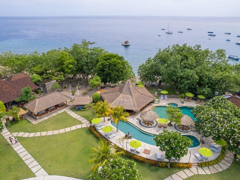 Luftaufnahme eines Resorts mit Pool, Garten und Blick auf das Meer mit Booten.