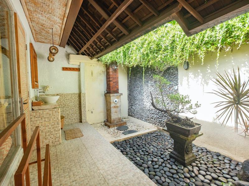 Offener Innenhof mit Wasserbrunnen, Steinboden und grünen Pflanzen unter Holzdach.