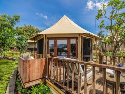 Alloggio simile a una tenda con terrazza e giardino sotto un cielo soleggiato.