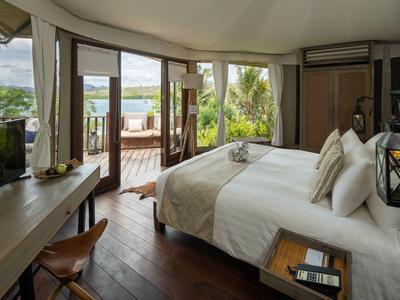 Camera d'hotel moderna con letto matrimoniale e accesso a terrazza con vista sul lago.