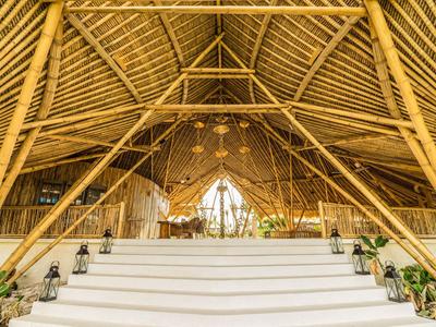 Duże schody prowadzą do jasnego pomieszczenia z bambusowym sufitem i dekoracyjnymi lampami.