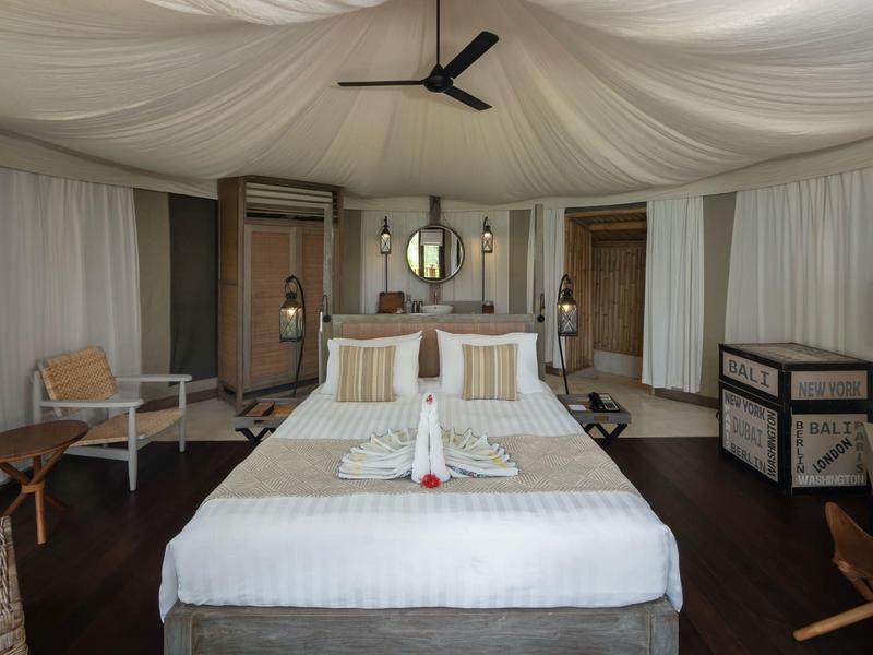 Elegante camera d'hotel con letto a baldacchino bianco, pavimento in legno e decorazioni sobrie.