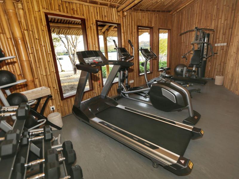 Palestra con tapis roulant, manubri e altre attrezzature su un pavimento in legno.