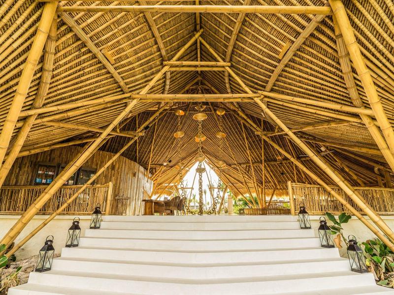 Ampia struttura in bambù con scale bianche e piante in un resort o hotel.