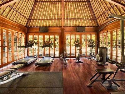 Een stijlvol ingerichte fitnessruimte met houten vloer en grote ramen in een hotel.